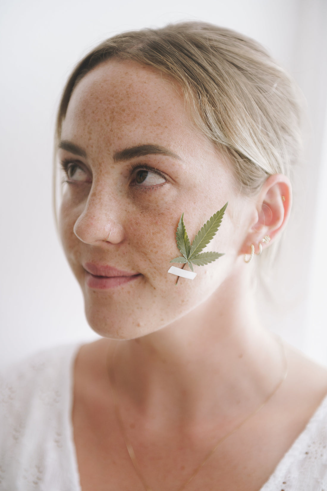 Mujer con hoja de cannabis en la cara, simbolizando el uso de CBD en cuidado personal.