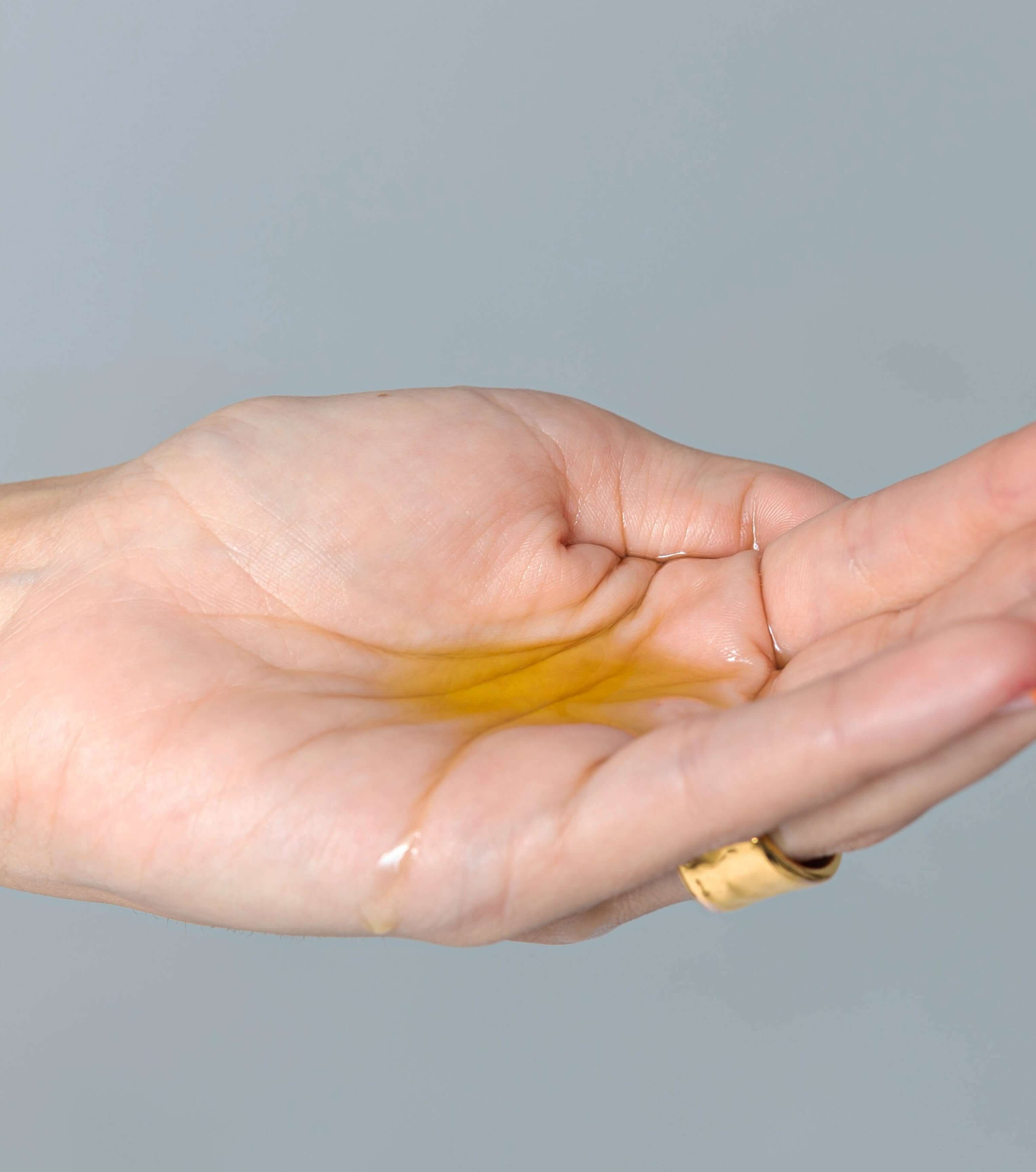Aceite corporal de CBD y jojoba en la palma de una mano, mostrando su textura y brillo.