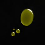 Drops of green oil on a black background, showcasing a natural CBD+CBG oil texture.
