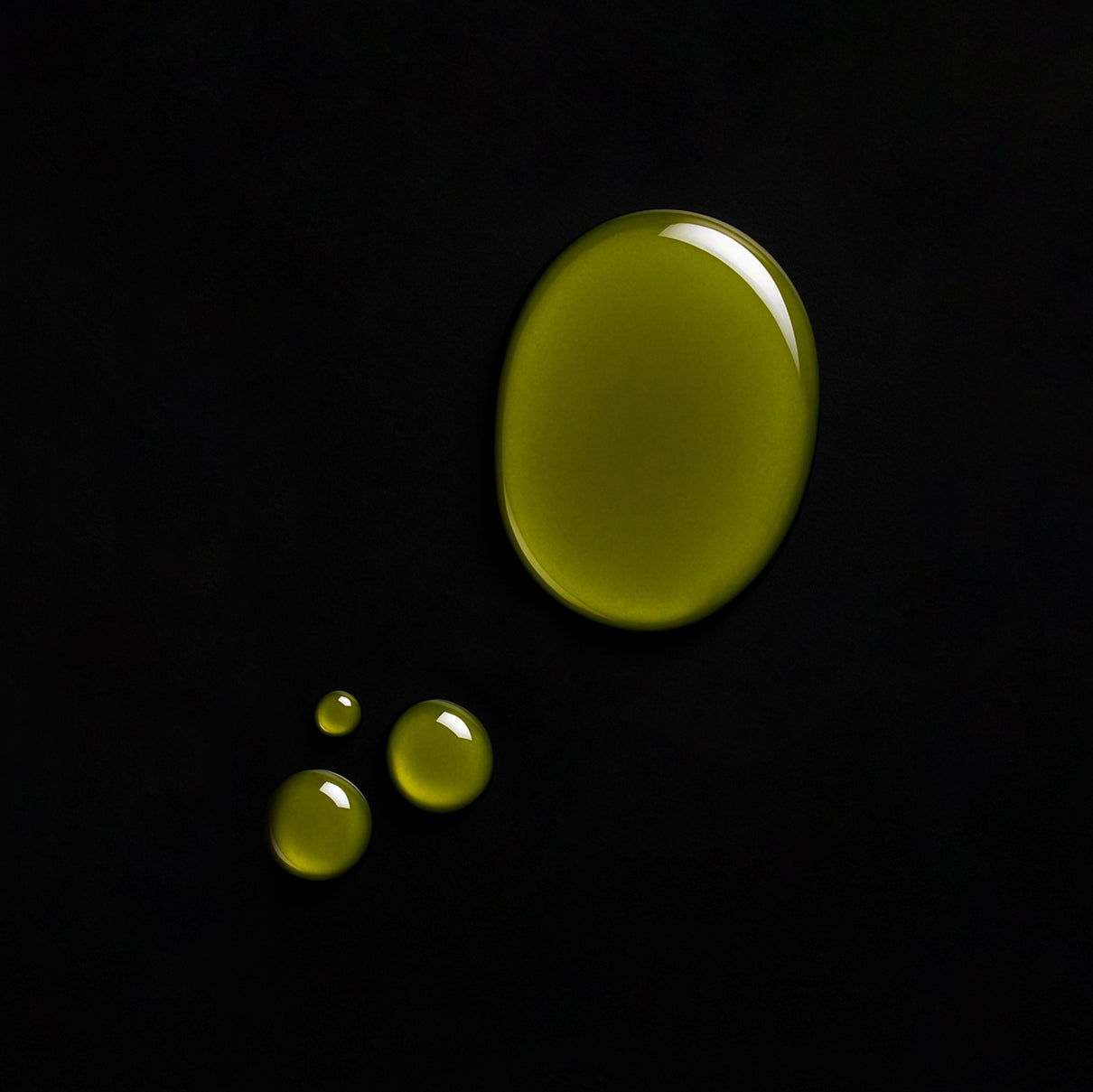 Drops of green oil on a black background, showcasing a natural CBD+CBG oil texture.